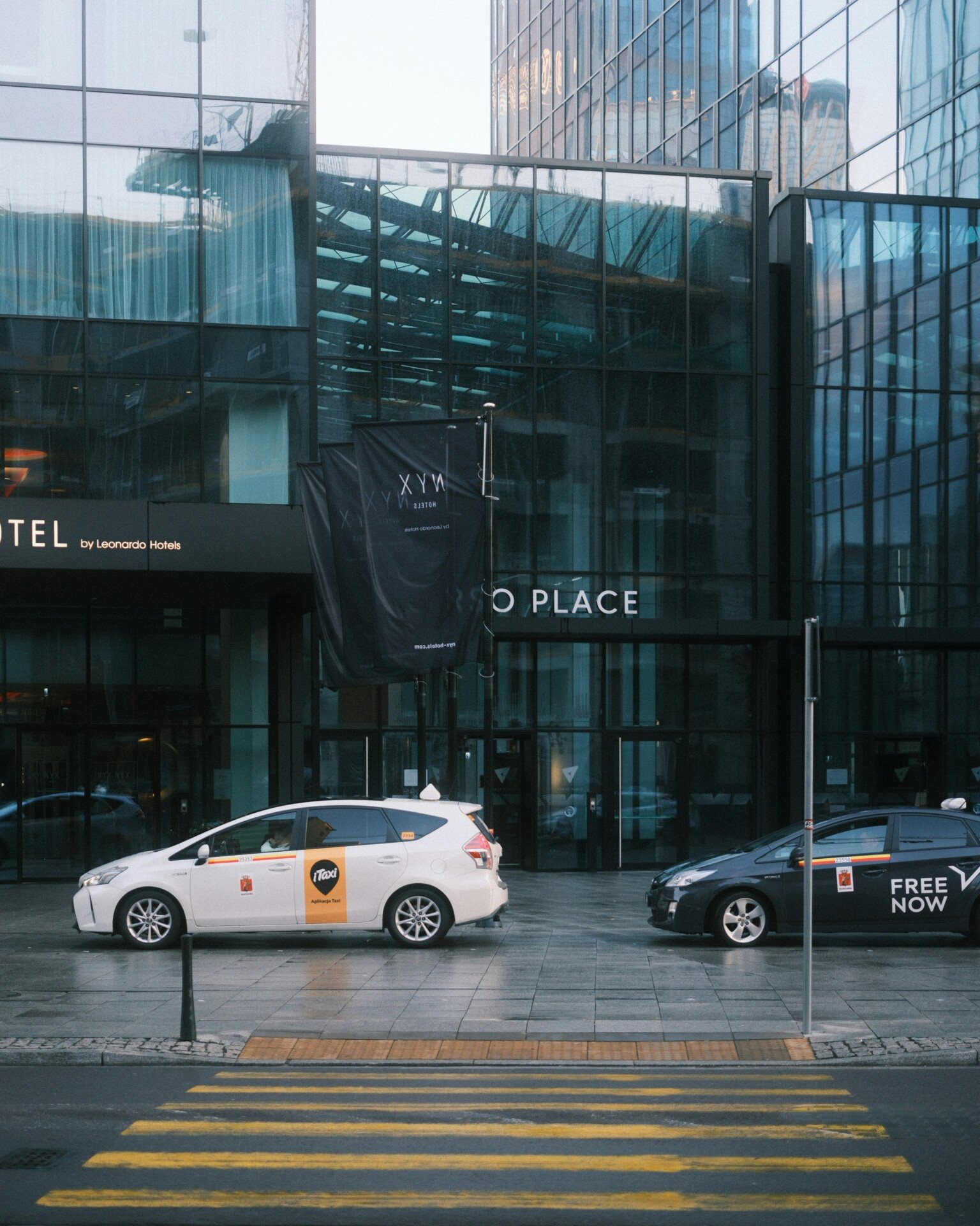 A taxi cab is parked in front of a hotel